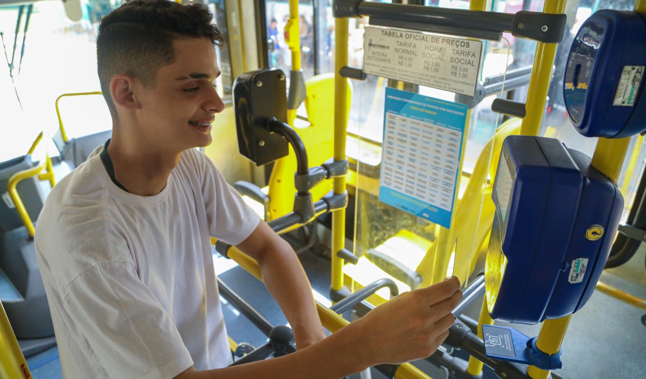 estudante passando a carteira no leitor do ônibus